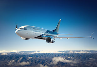 Boeing Business Jet flying over mountains 