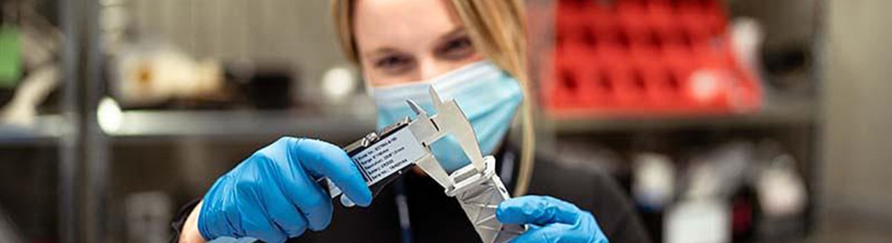 Woman measuring an item with calipers.