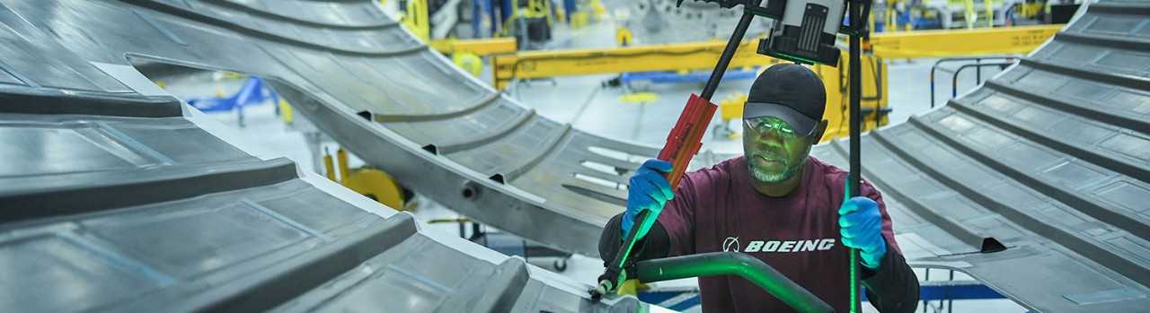 Worker in bump cap and safety glasses working on plane.