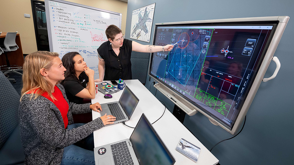 Three women discuss aircraft communication data on screen