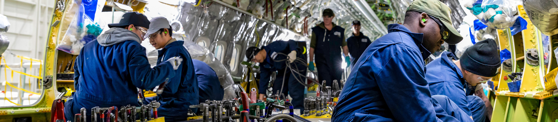 Employees performing work inside of airplane.